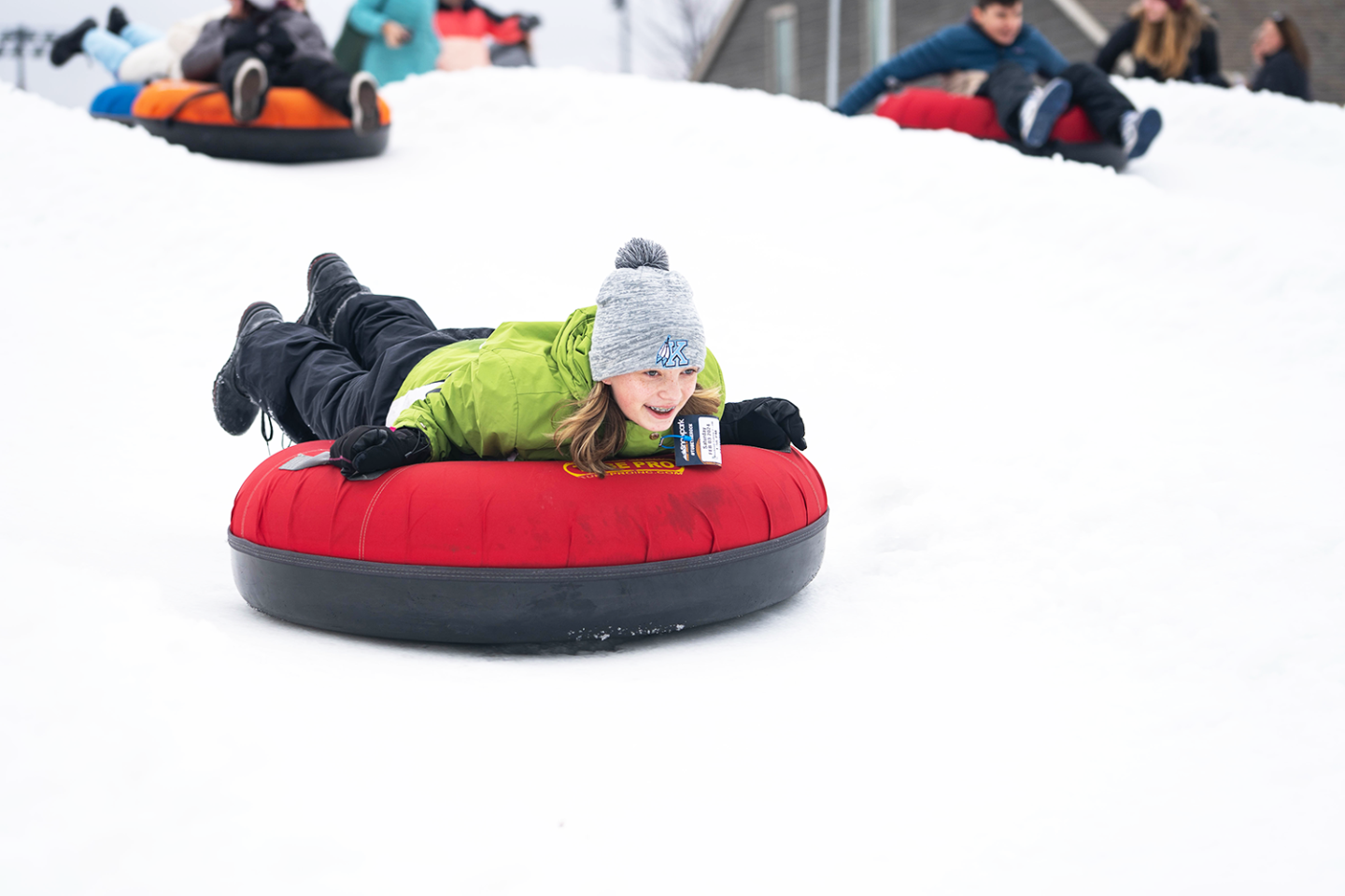 kid riding snow tube downhill, head first
