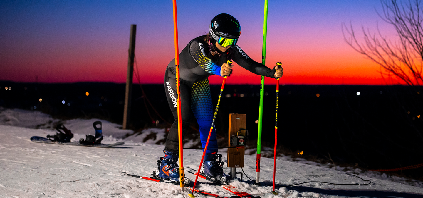 Ski racer waiting at beginning of track, with colourful sunset behind them