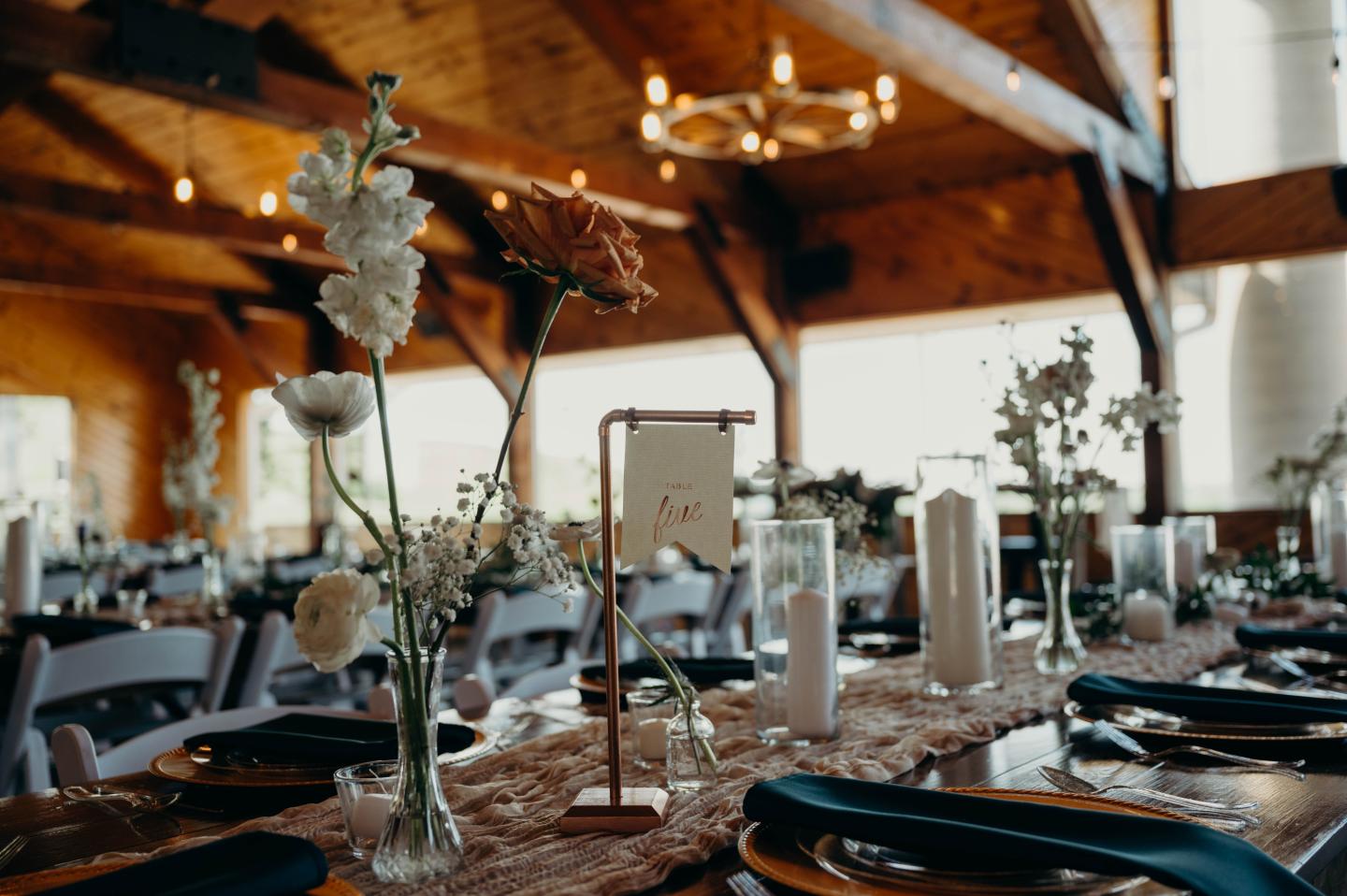Rustic banquet hall with floral table centerpieces and candles.