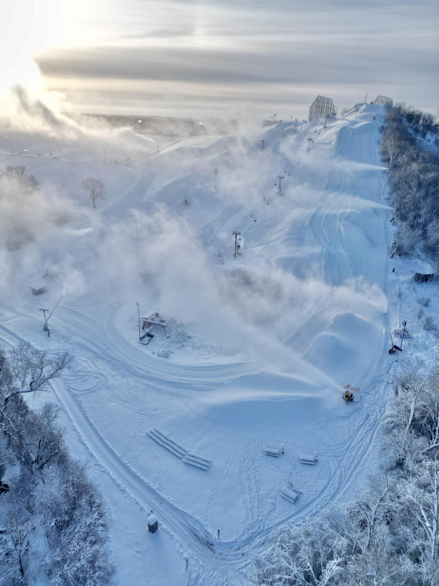 Snow-covered ski resort with trees and misty sunlight.