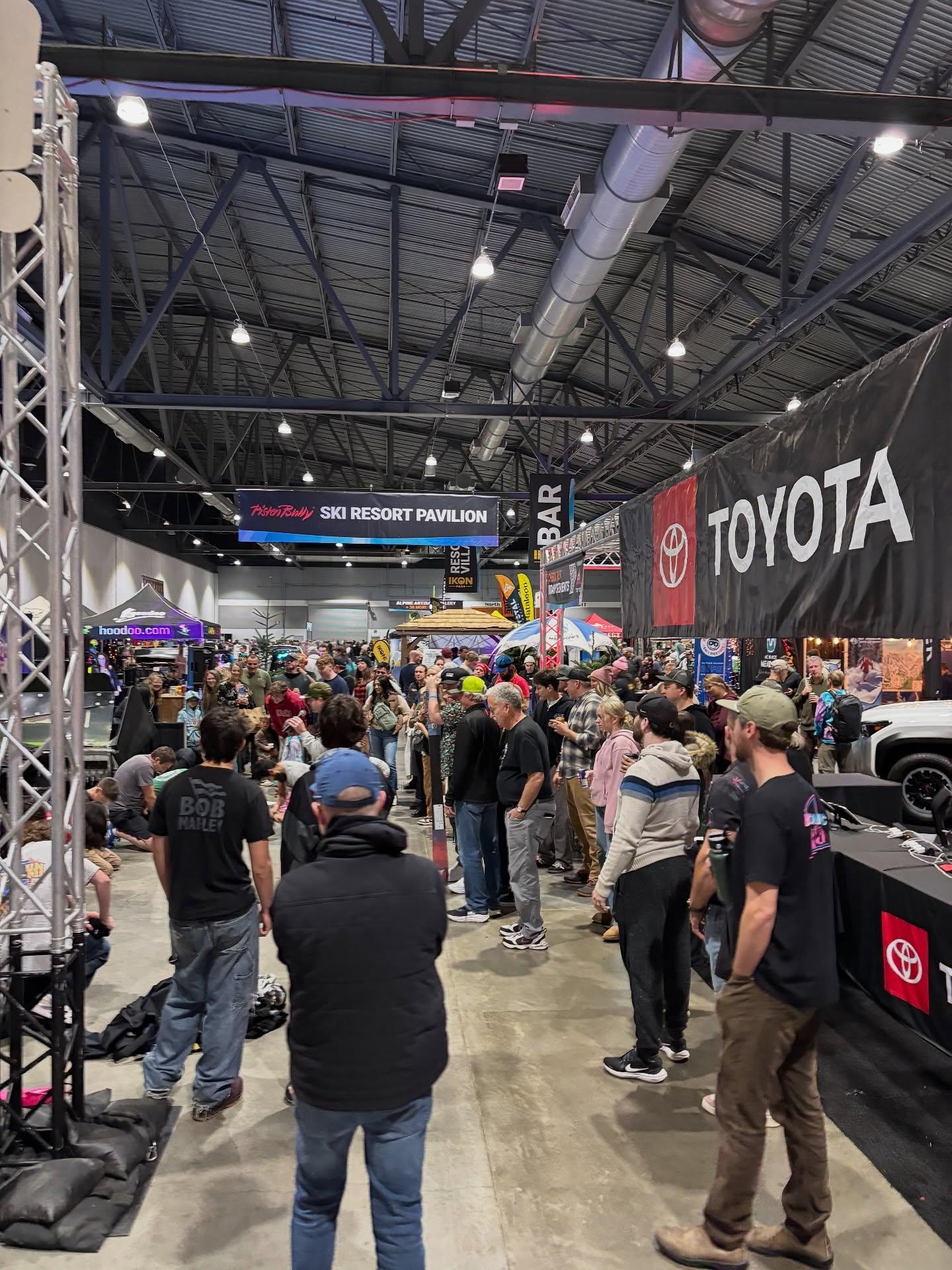 Crowded Toyota exhibition booth inside a large auto show hall.