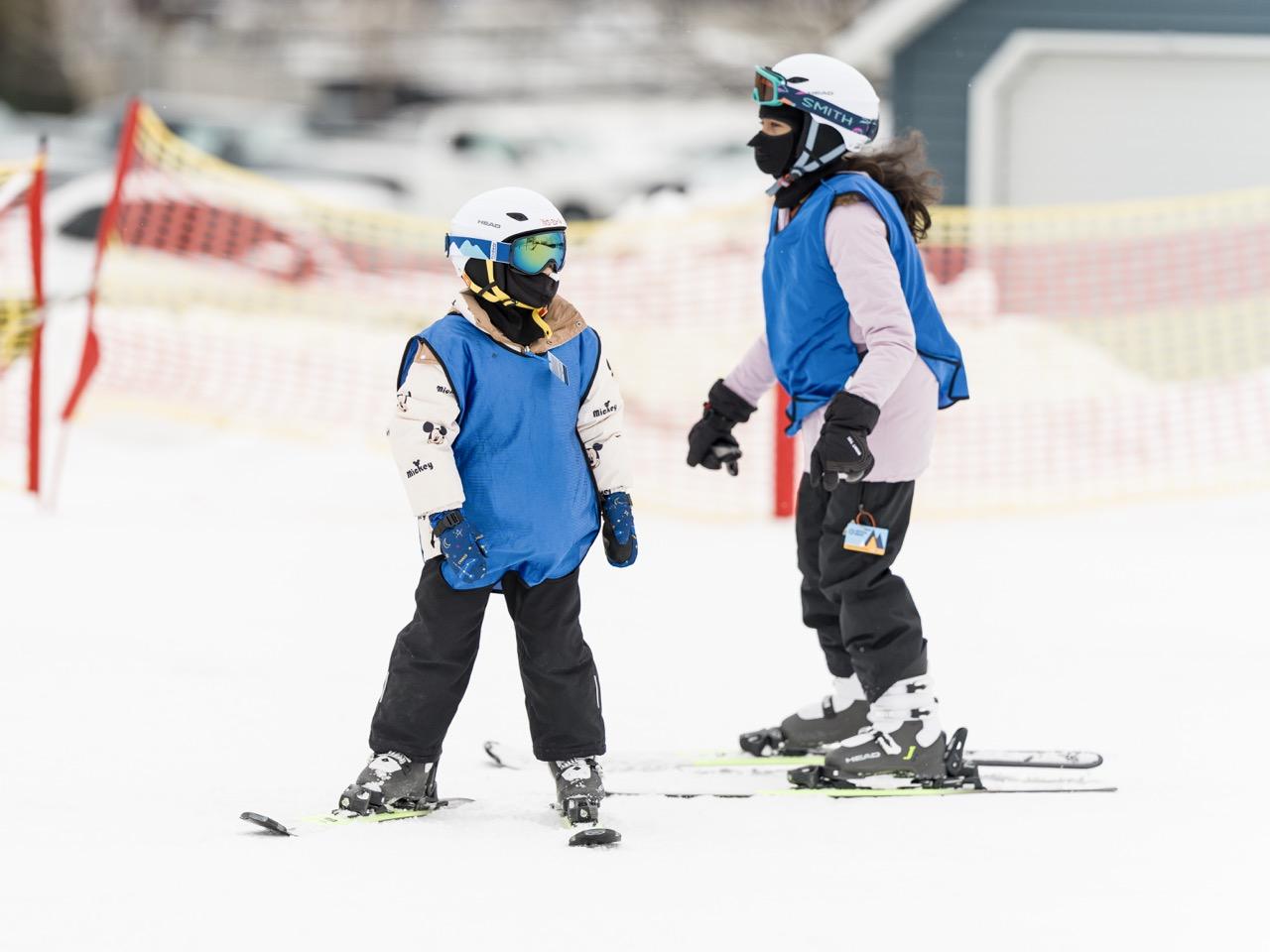 Adult skier assisting a child skier on a snowy slope.