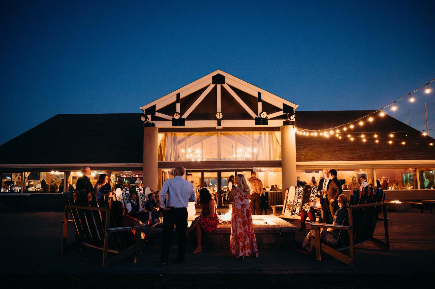 Outdoor evening wedding under a warmly lit pavilion with string lights.
