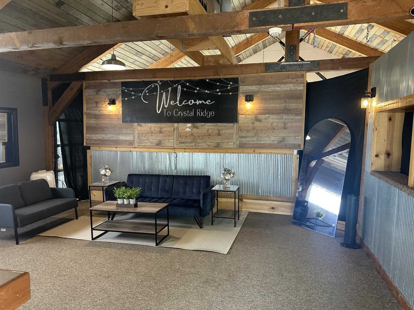 Rustic salon reception area with black chairs, wood beams, and a welcome sign.