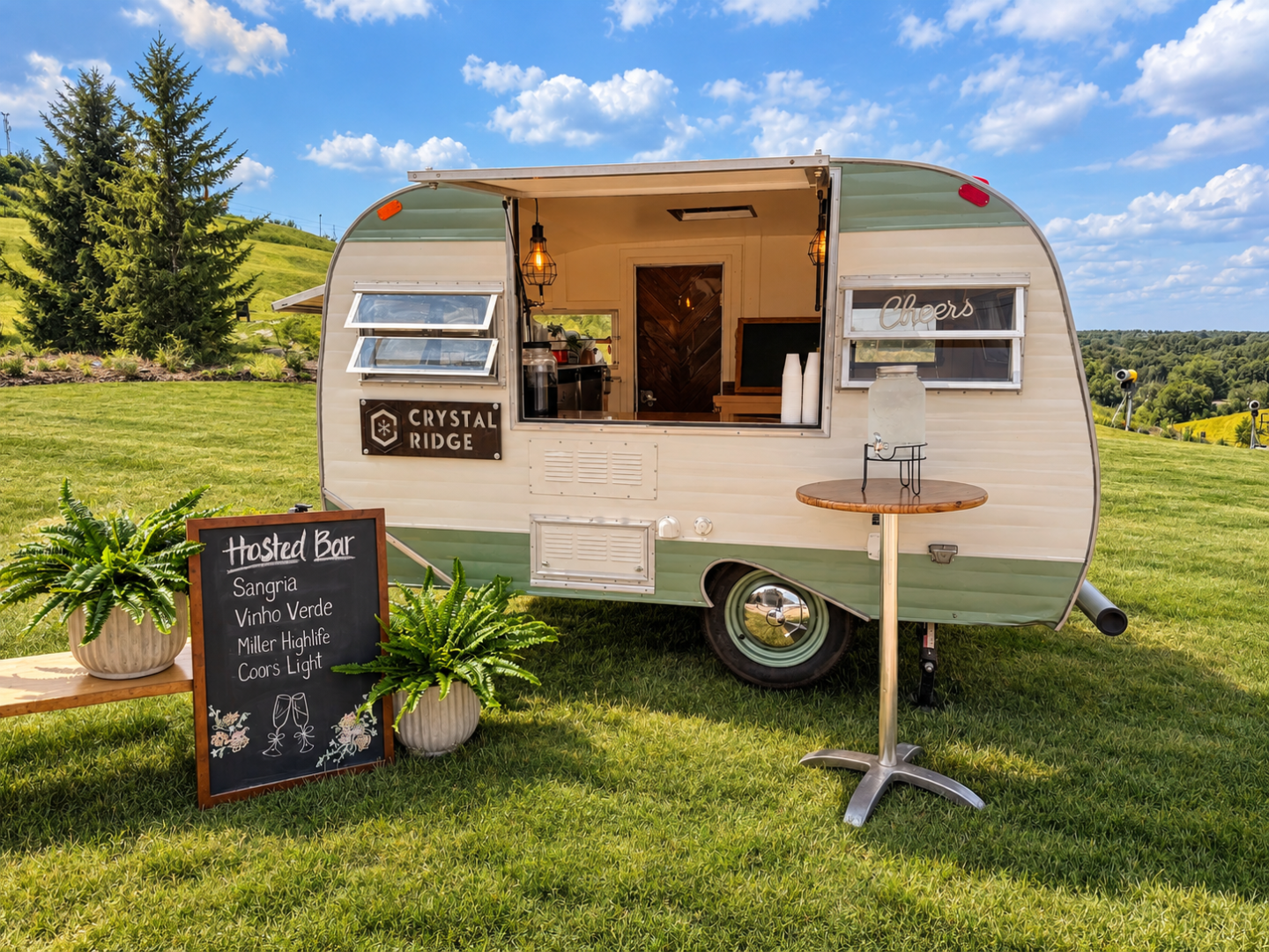 Vintage camper bar with open serving window on a grassy lawn.